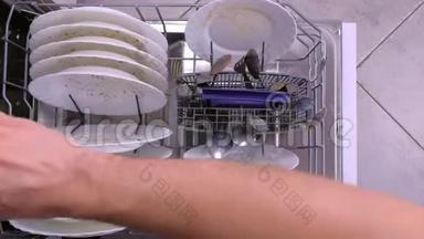 男人`手推洗碗机篮子和脏盘子。